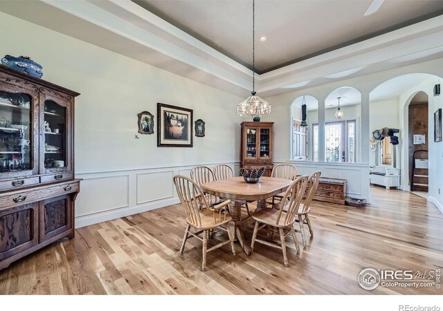 dining area with light hardwood / wood-style flooring and a tray ceiling