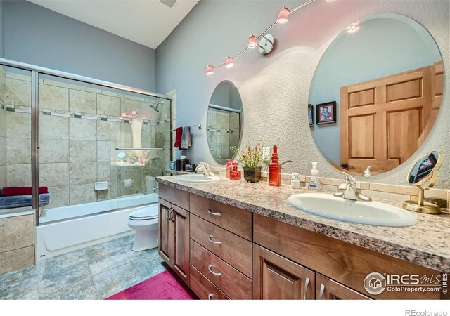 full bathroom featuring shower / bath combination with glass door, vanity, tile patterned flooring, and toilet