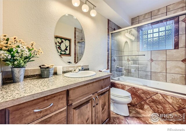 full bathroom with toilet, bath / shower combo with glass door, and vanity