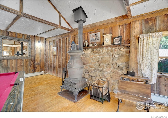 interior space with hardwood / wood-style flooring, a wood stove, and a baseboard radiator