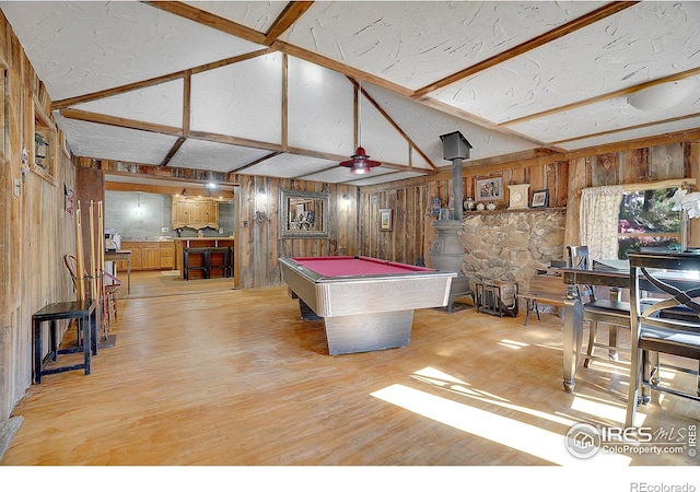 recreation room featuring vaulted ceiling with beams, light hardwood / wood-style floors, a wood stove, and billiards