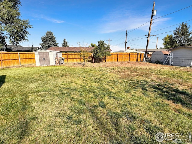 view of yard with a fenced backyard, an outdoor structure, and a shed