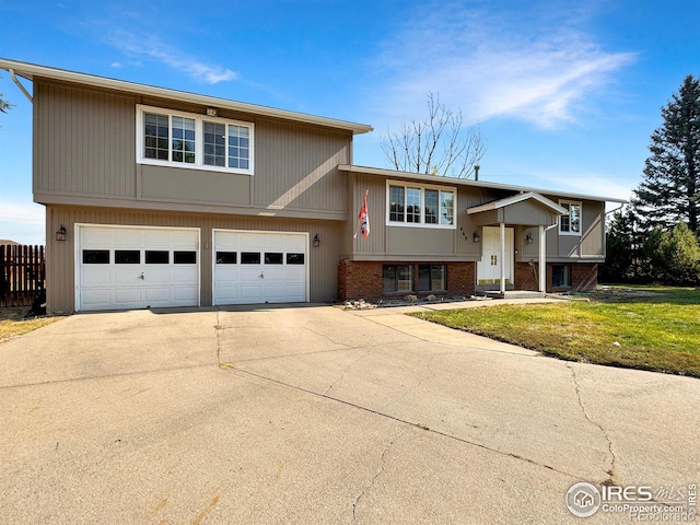 bi-level home featuring a garage, driveway, fence, a front yard, and brick siding