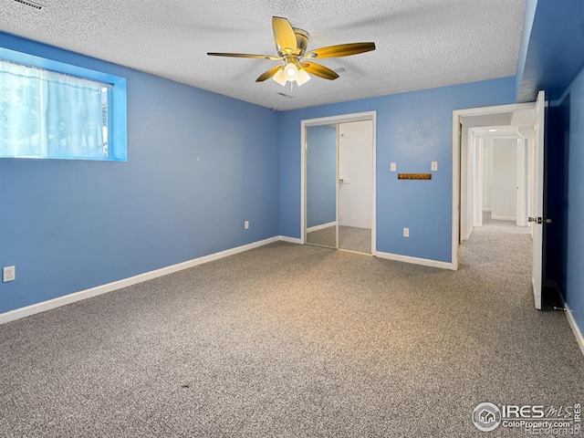 unfurnished bedroom with ceiling fan, carpet floors, a textured ceiling, and a closet
