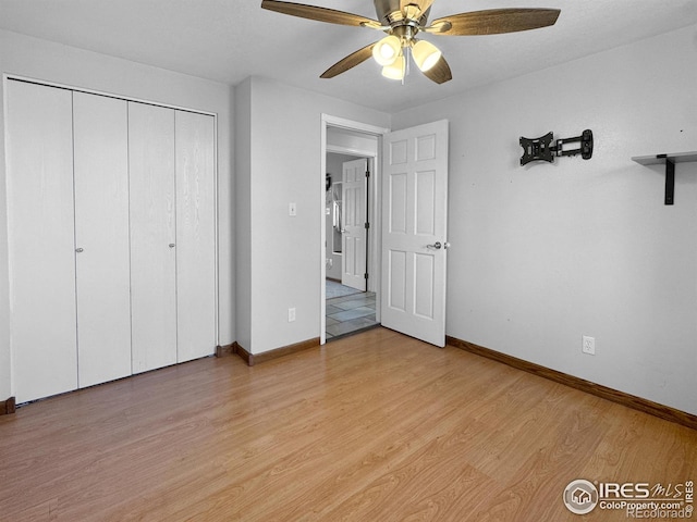 unfurnished bedroom featuring baseboards, a ceiling fan, light wood finished floors, and a closet
