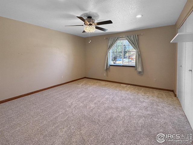 empty room featuring visible vents, a ceiling fan, carpet floors, baseboards, and a textured ceiling
