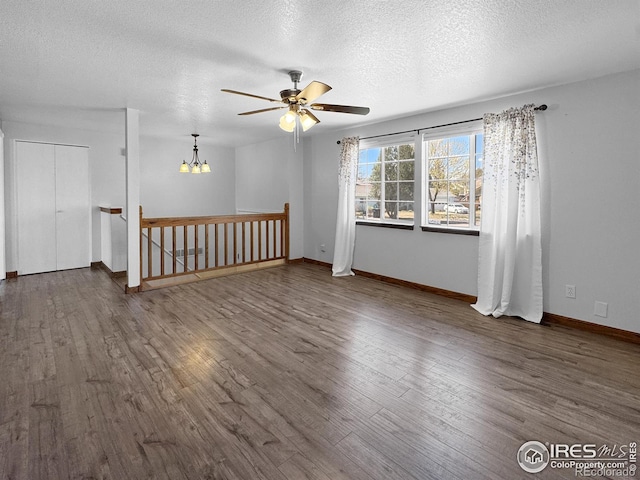 interior space featuring wood finished floors, a textured ceiling, baseboards, and ceiling fan with notable chandelier