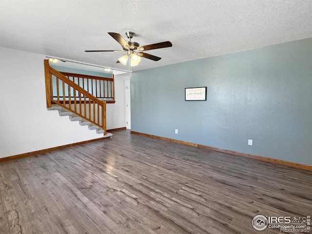 unfurnished living room featuring stairway, wood finished floors, baseboards, a textured ceiling, and ceiling fan