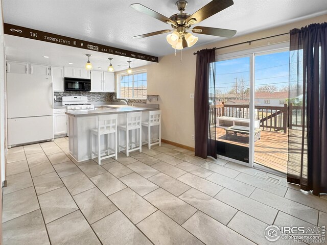 kitchen featuring light tile patterned floors, white appliances, decorative backsplash, a peninsula, and white cabinetry