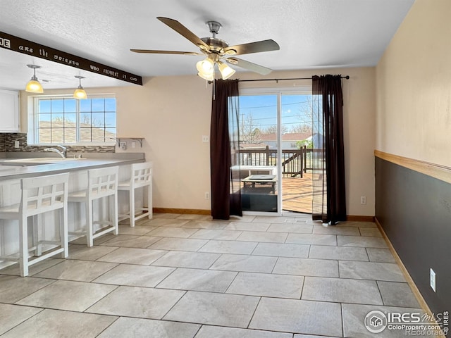 dining area with a textured ceiling, ceiling fan, and a healthy amount of sunlight