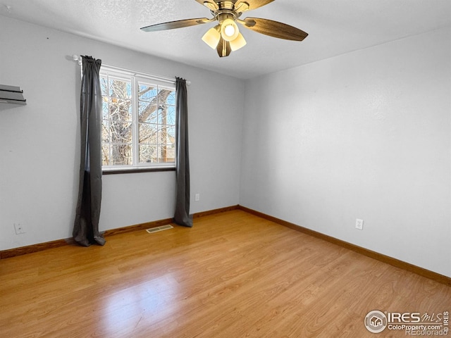 empty room with ceiling fan, baseboards, visible vents, and light wood-style flooring
