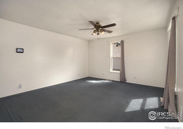 unfurnished room with ceiling fan, a textured ceiling, and dark carpet