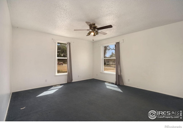 carpeted empty room featuring ceiling fan and a textured ceiling