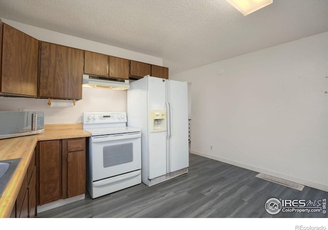 kitchen featuring a textured ceiling, dark wood-type flooring, white appliances, and butcher block counters