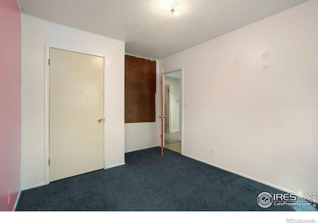 unfurnished bedroom with dark carpet and a textured ceiling