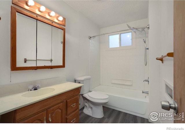 full bathroom with toilet, wood-type flooring, tiled shower / bath combo, vanity, and a textured ceiling