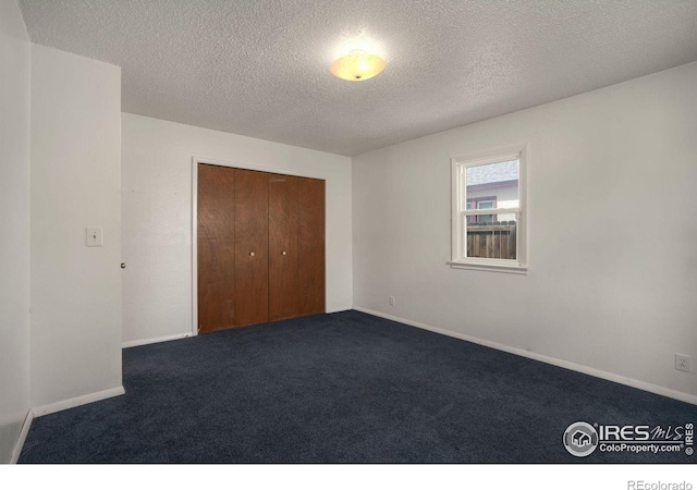 unfurnished bedroom featuring carpet floors, a textured ceiling, and a closet