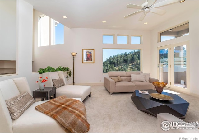 carpeted living room with a towering ceiling, a wealth of natural light, and ceiling fan