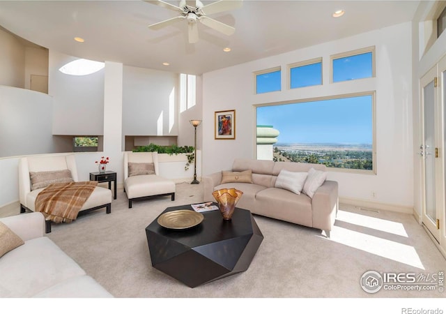 carpeted living room with ceiling fan, a towering ceiling, and a wealth of natural light