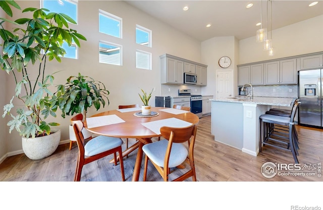 dining room with light hardwood / wood-style flooring, a high ceiling, and sink