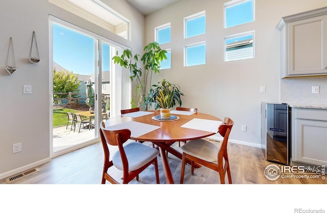 dining area featuring wine cooler and light hardwood / wood-style flooring