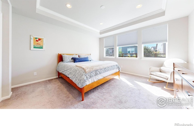 carpeted bedroom with a tray ceiling and crown molding