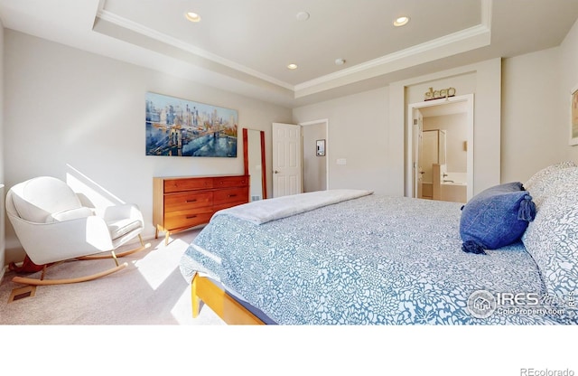 carpeted bedroom featuring a tray ceiling, ensuite bath, and ornamental molding