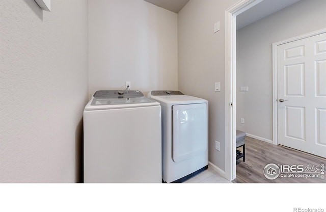 clothes washing area with washer and dryer and light hardwood / wood-style flooring