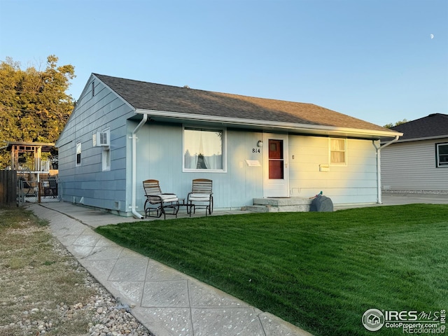 back of property with a wall mounted AC and a lawn