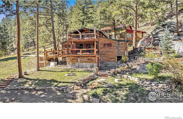 rear view of house featuring a yard, a wooden deck, and a balcony