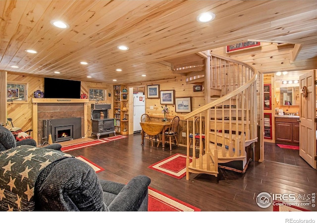 living room with a premium fireplace, wooden walls, dark wood-type flooring, and wooden ceiling