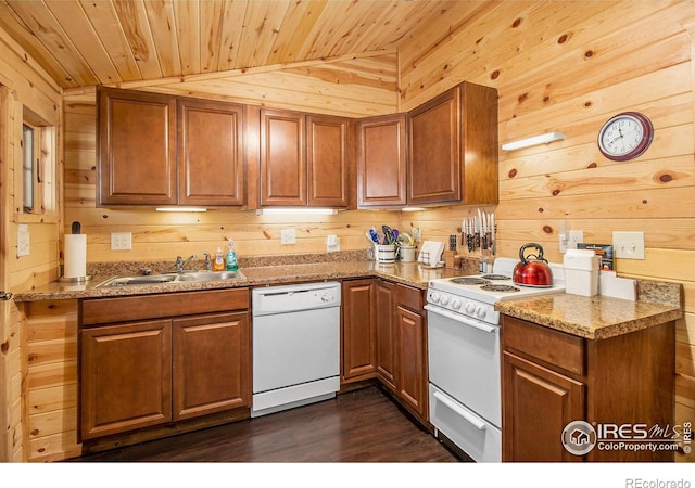 kitchen featuring wood walls, white appliances, vaulted ceiling, and sink