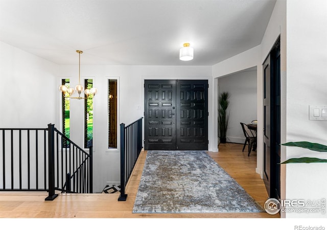 entryway with wood-type flooring and an inviting chandelier