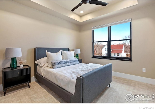 carpeted bedroom featuring ceiling fan and a raised ceiling