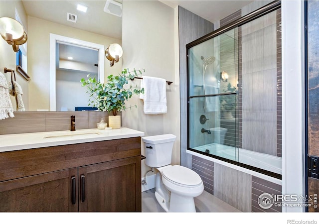 full bathroom featuring toilet, vanity, decorative backsplash, and combined bath / shower with glass door