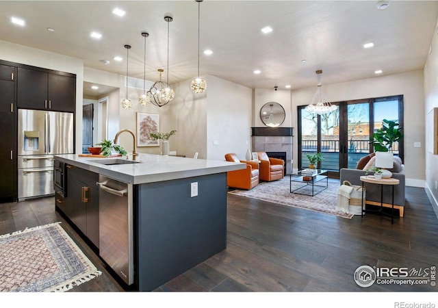 kitchen with decorative light fixtures, stainless steel fridge with ice dispenser, dark hardwood / wood-style flooring, and an island with sink