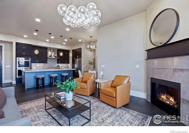 living room with a chandelier, dark hardwood / wood-style flooring, and a tiled fireplace