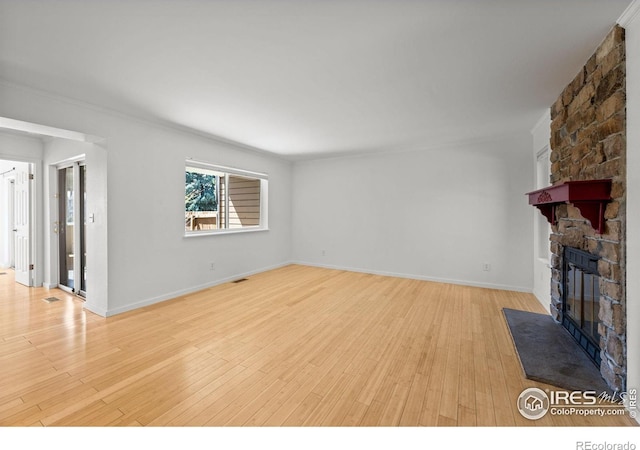 unfurnished living room with light hardwood / wood-style flooring and a stone fireplace