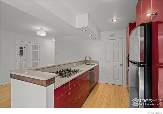 kitchen featuring appliances with stainless steel finishes, sink, and light hardwood / wood-style flooring