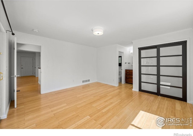 unfurnished bedroom featuring ornamental molding and light hardwood / wood-style floors