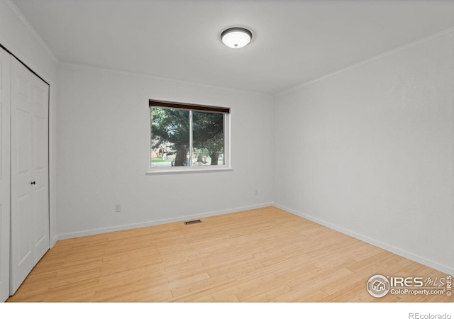 unfurnished bedroom with crown molding, a closet, and light hardwood / wood-style floors