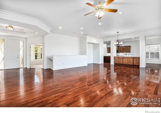 unfurnished living room with ceiling fan with notable chandelier, dark hardwood / wood-style flooring, and crown molding