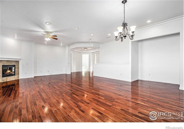 unfurnished living room featuring a tiled fireplace, dark wood-type flooring, ceiling fan with notable chandelier, and ornamental molding