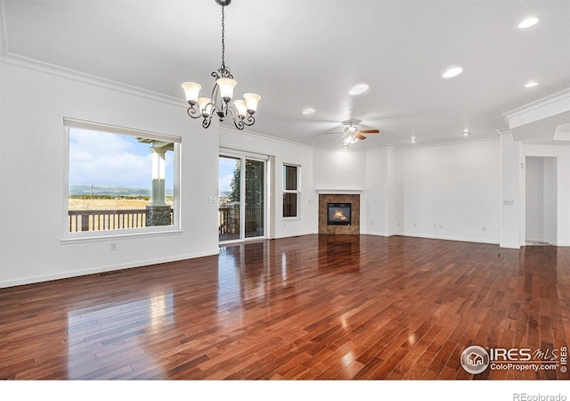 unfurnished living room featuring ceiling fan with notable chandelier, dark wood-type flooring, and crown molding