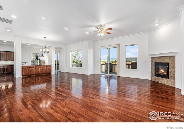 unfurnished living room with crown molding, a fireplace, dark hardwood / wood-style flooring, and ceiling fan with notable chandelier