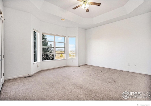 carpeted spare room featuring ceiling fan and a tray ceiling