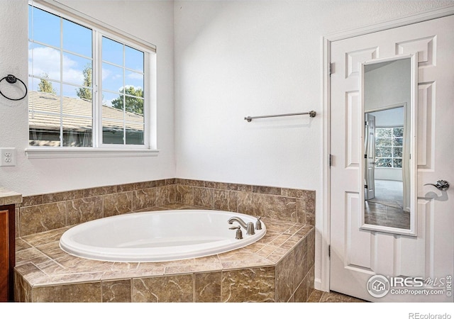 bathroom with vanity, a wealth of natural light, and tiled tub