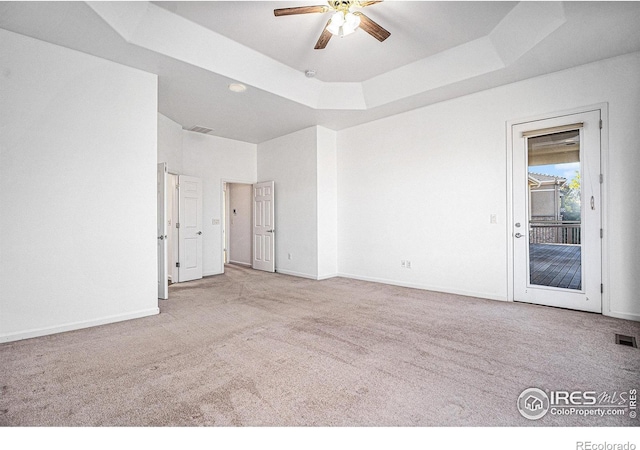 empty room featuring light carpet, ceiling fan, and a tray ceiling