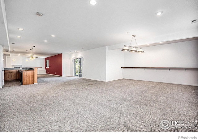 unfurnished living room featuring carpet, ceiling fan, and sink