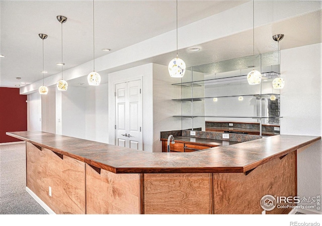 kitchen with decorative light fixtures and carpet floors